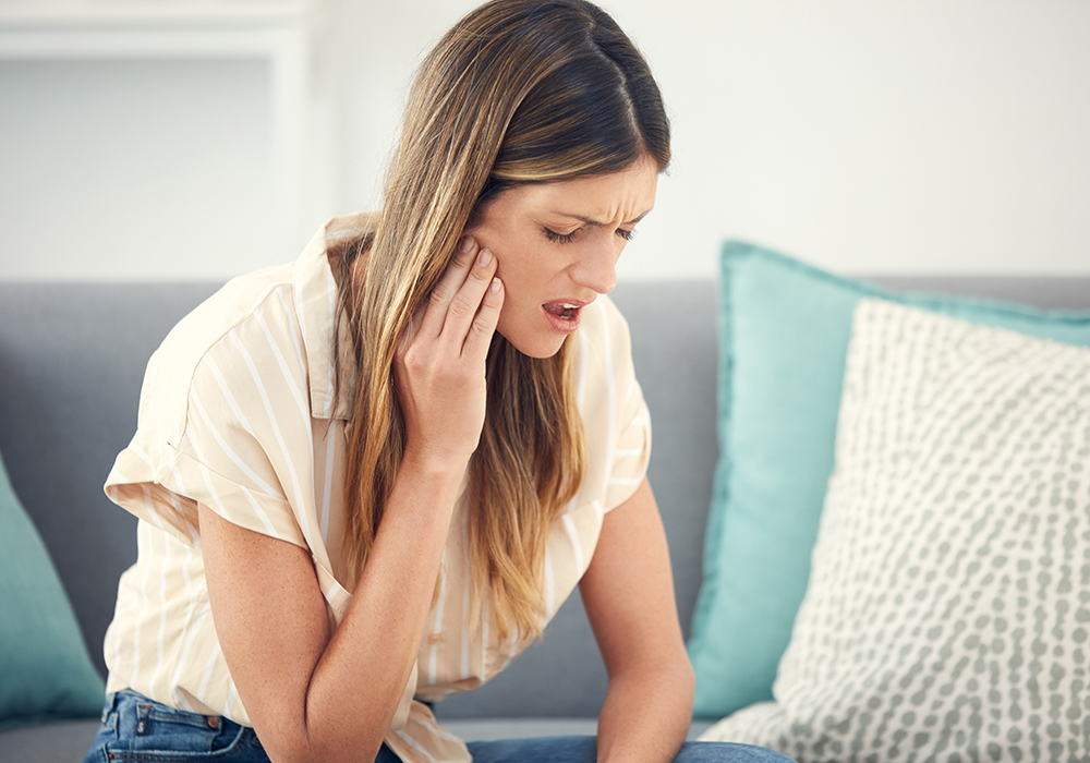 Woman in pain needing urgent dental care at home