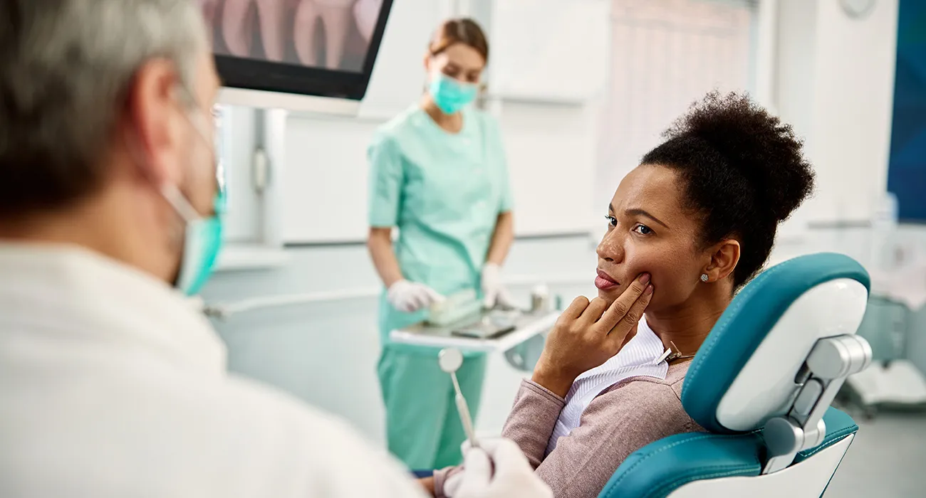 black woman holding mouth in pain