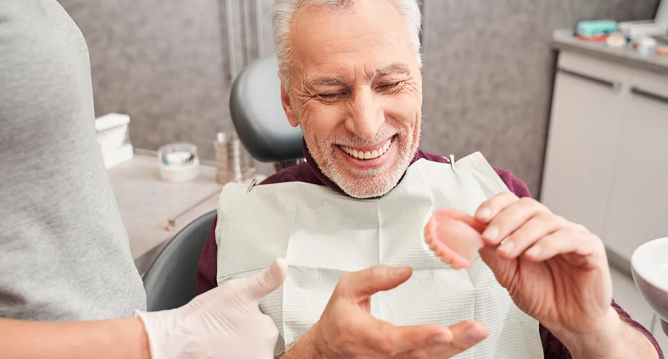 older man smiling and looking at top denture