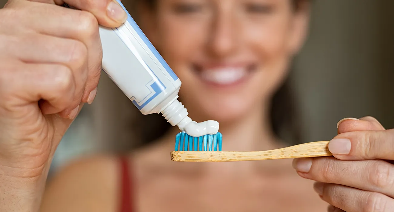 woman putting toothpaste on toothbrush
