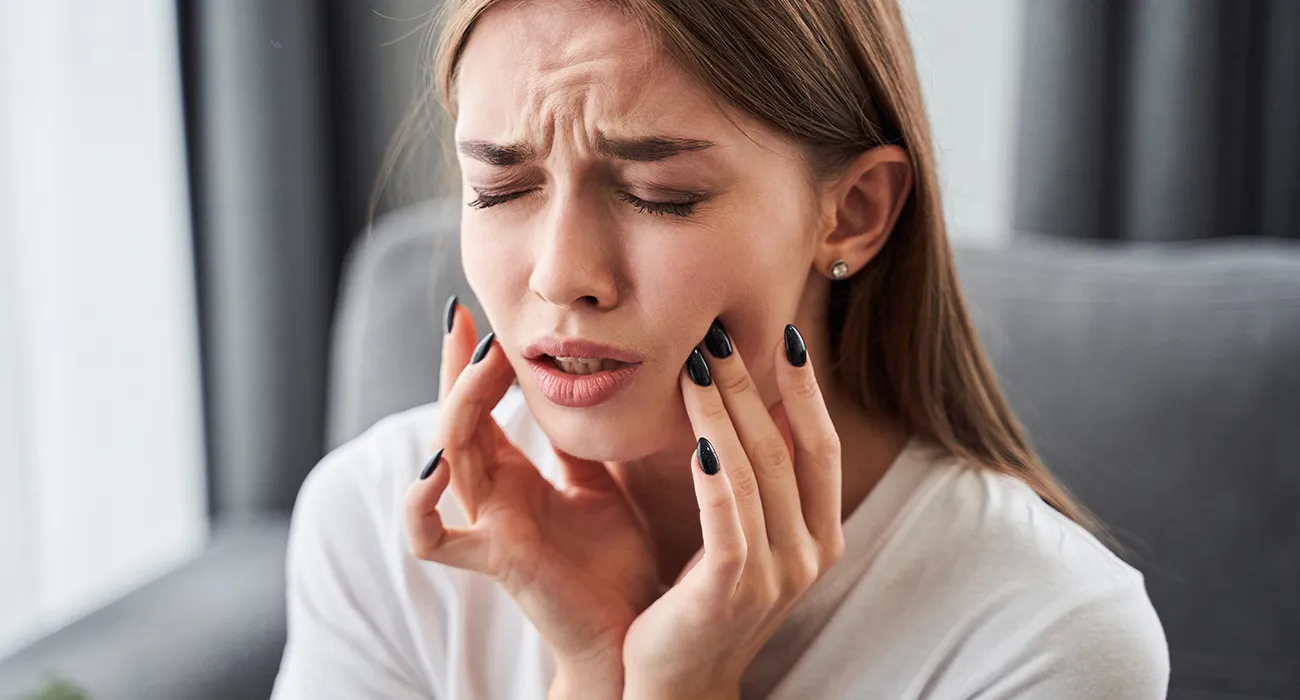Woman holding her jaw due to tooth pain